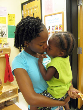 Woman holding child and giving her a kiss