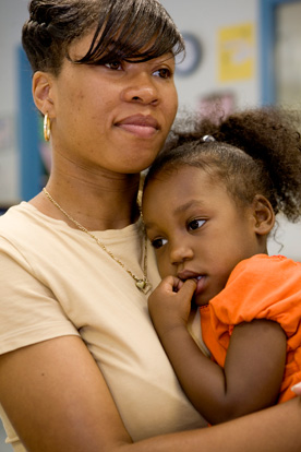 Woman holds young girl in her arms as the girl rests on the woman's chest.