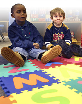 Two children sit on an activity mat