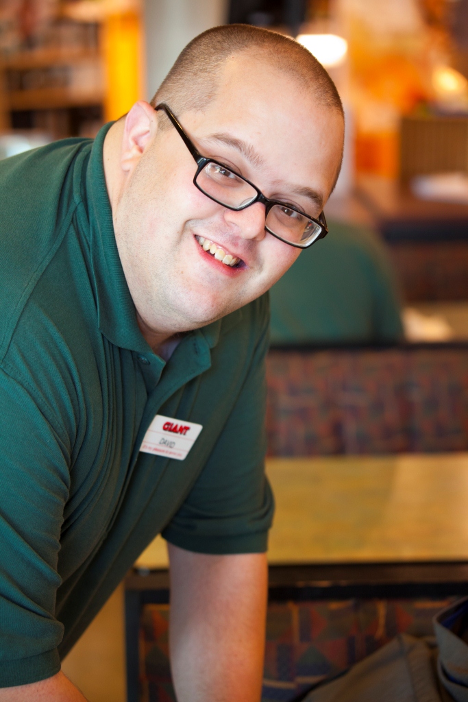 Man dressed in grocery store uniform smils for the camera