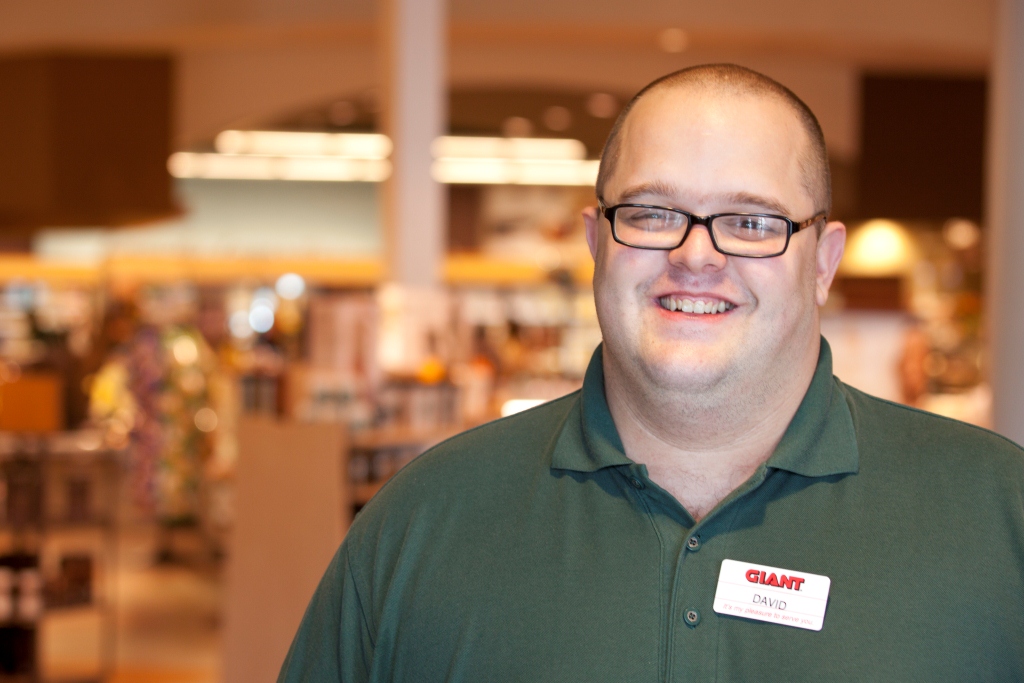Man in grocery store work uniform smiles for the camera