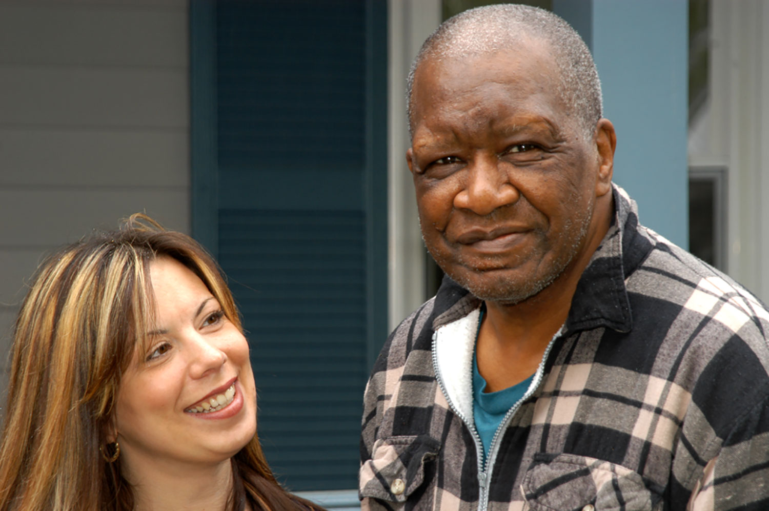 Man smiles for the camera while woman standing next to him smiles at him