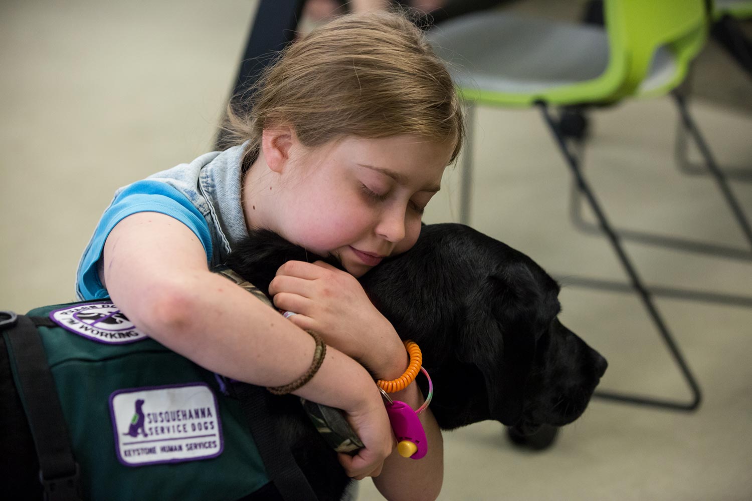 Lorelie hugs Mandu, a black Lab service dog from Susquehanna Service Dogs