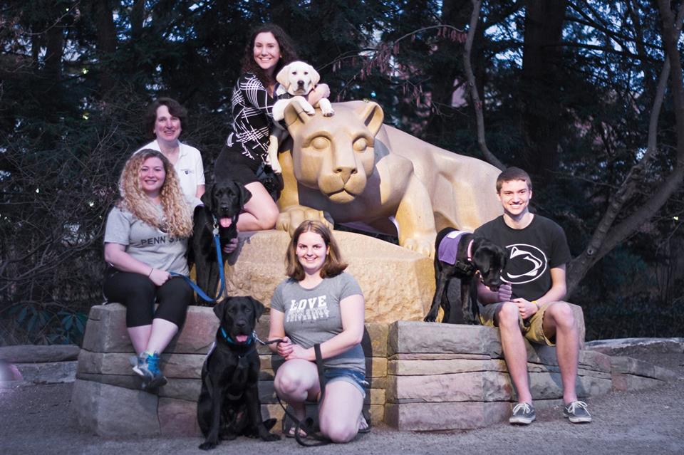 Penn State staff and students and SSD service dogs in training pose at the Nittany Lion Shrine at the University Park Campus